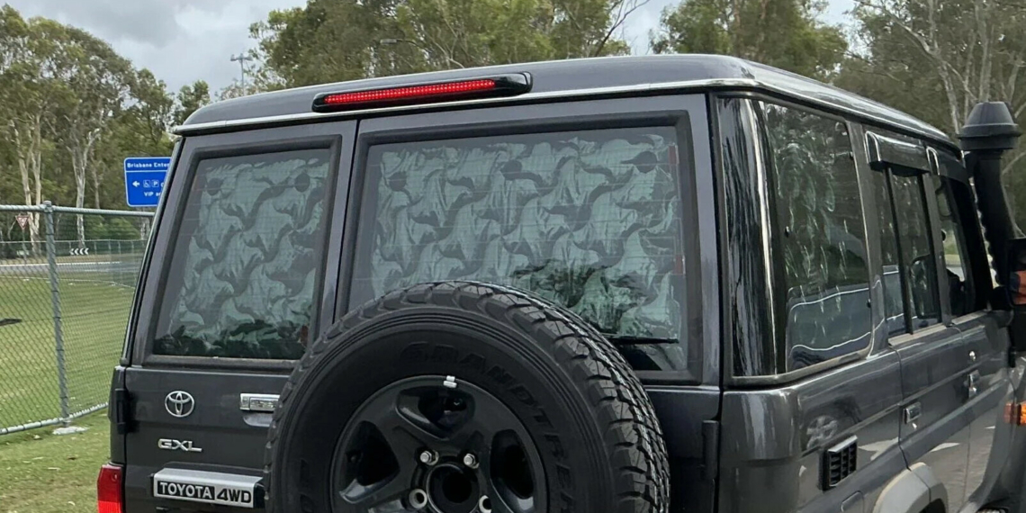 A Toyota LandCruiser 70 Series with reflective material blocking its rear windows